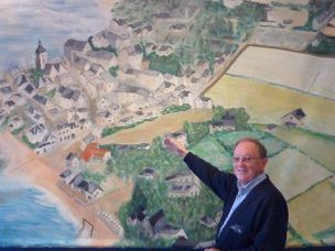 Gilles Renaudeau, président de la Maison du patrimoine, devant une peinture représentant une vue d‘ensemble de la commune de Piriac dans les années 50.